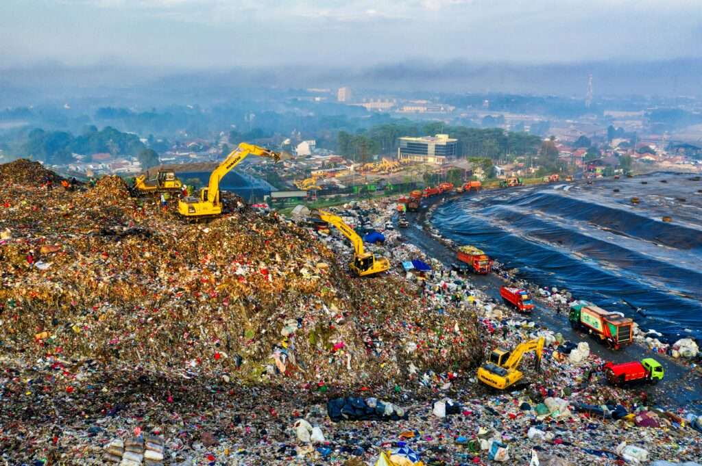 Aerial view showing heavy machinery at a landfill site in West Java, Indonesia.